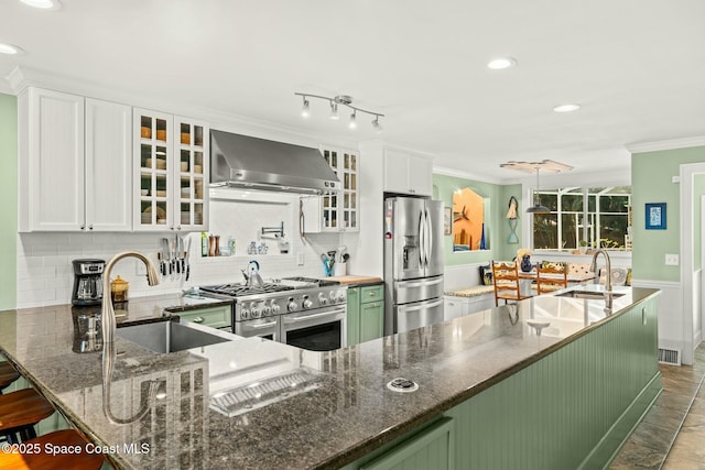 kitchen with crown molding, stainless steel appliances, a sink, and wall chimney exhaust hood