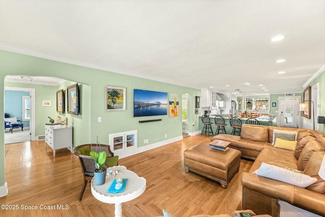 living area with arched walkways, baseboards, recessed lighting, and ornamental molding