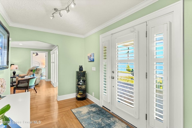 entrance foyer featuring track lighting, baseboards, ornamental molding, and a textured ceiling