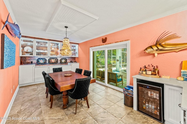 dining area with beverage cooler, a chandelier, ornamental molding, and a bar