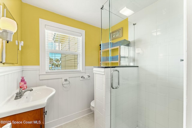 full bath with wainscoting, vanity, a stall shower, and toilet