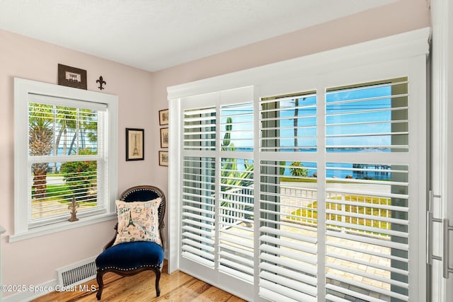 sitting room with a healthy amount of sunlight, wood finished floors, and visible vents