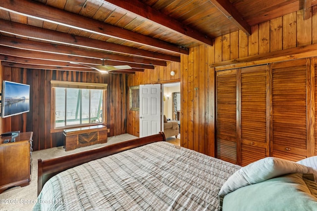 bedroom with wooden walls, carpet flooring, beam ceiling, wood ceiling, and a closet