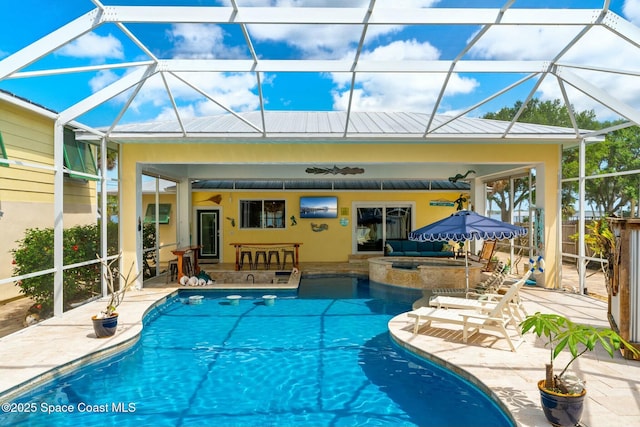 view of pool with fence, a pool with connected hot tub, a patio, a ceiling fan, and a lanai