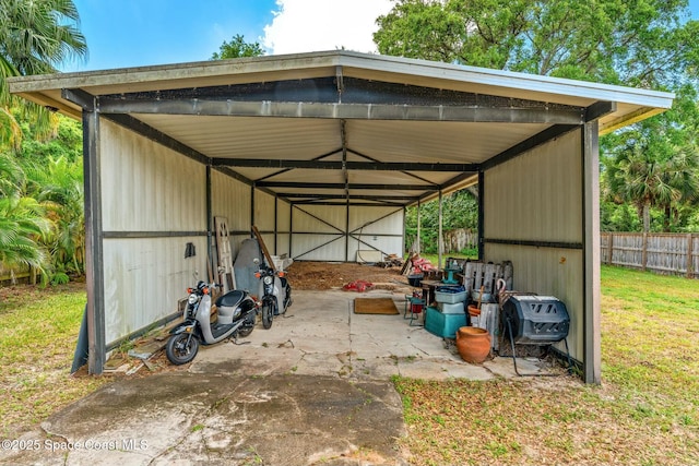 view of pole building with fence, a detached carport, and a lawn