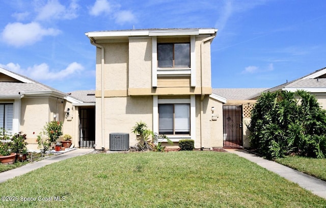 view of front of home with central air condition unit, a gate, a front lawn, and stucco siding