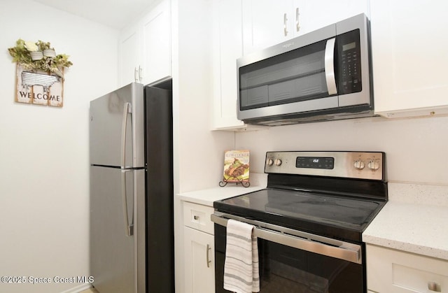 kitchen with appliances with stainless steel finishes, white cabinets, and light stone countertops