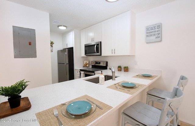 kitchen with light countertops, white cabinets, appliances with stainless steel finishes, and electric panel