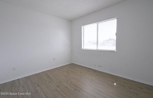 spare room with baseboards, a textured ceiling, and wood finished floors