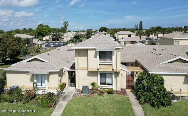 view of front facade with central AC unit, a front lawn, stucco siding, and a residential view