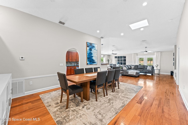 dining room with a skylight, a ceiling fan, light wood-style flooring, and visible vents
