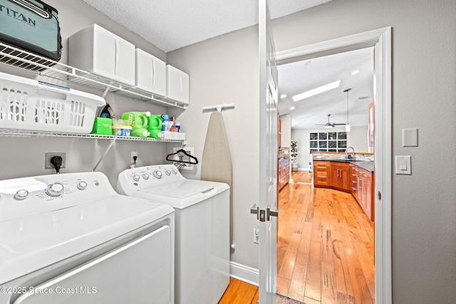 laundry room with ceiling fan, laundry area, a textured ceiling, light wood-style flooring, and washer and dryer