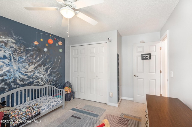 carpeted bedroom with a closet, a textured ceiling, ceiling fan, and baseboards