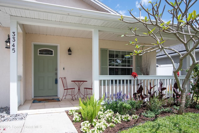 view of exterior entry with a porch and stucco siding