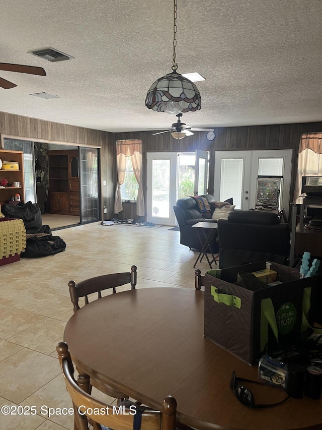 580 Hidden Creek Dr, Merritt Island, FL 32952 - tiled dining area with wooden walls, a ceiling fan, a textured ceiling, and visible vents