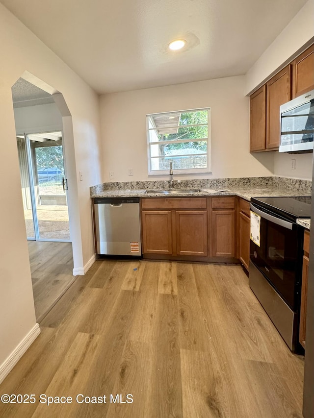 kitchen featuring stainless steel appliances, a wealth of natural light, a sink, and light wood-style flooring