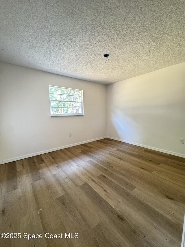 unfurnished room featuring baseboards, a textured ceiling, and wood finished floors