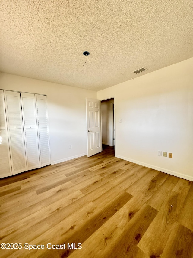 unfurnished bedroom featuring baseboards, a textured ceiling, and visible vents