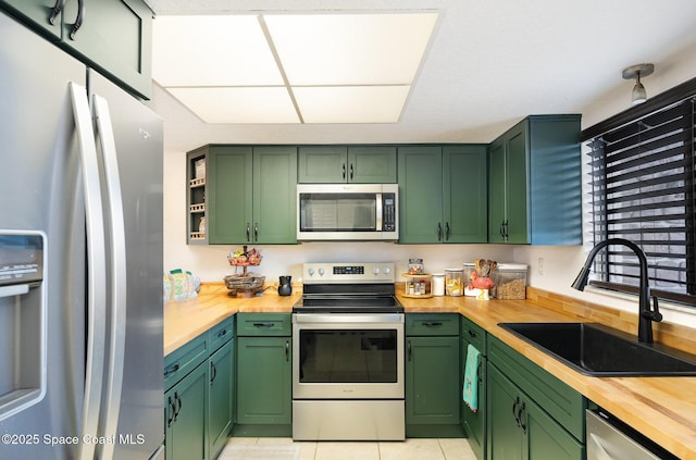 100 Canebreakers Dr Unit 112, Cocoa, FL 32927 - kitchen with wooden counters, a sink, light tile patterned floors, green cabinets, and stainless steel appliances