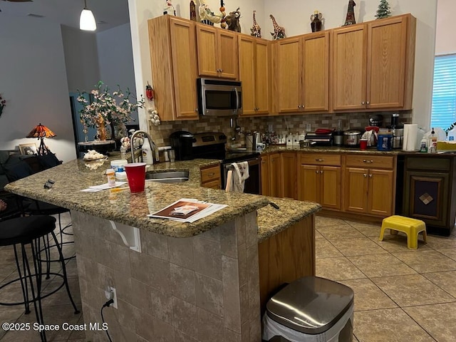 kitchen with a sink, a peninsula, backsplash, and stainless steel appliances