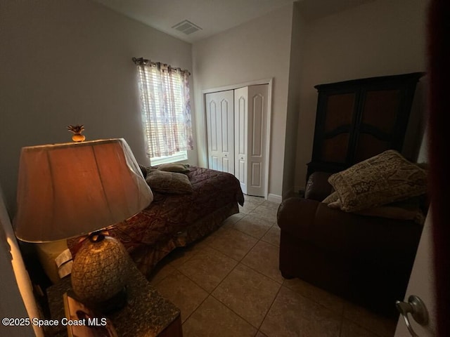 bedroom with tile patterned flooring, visible vents, and a closet