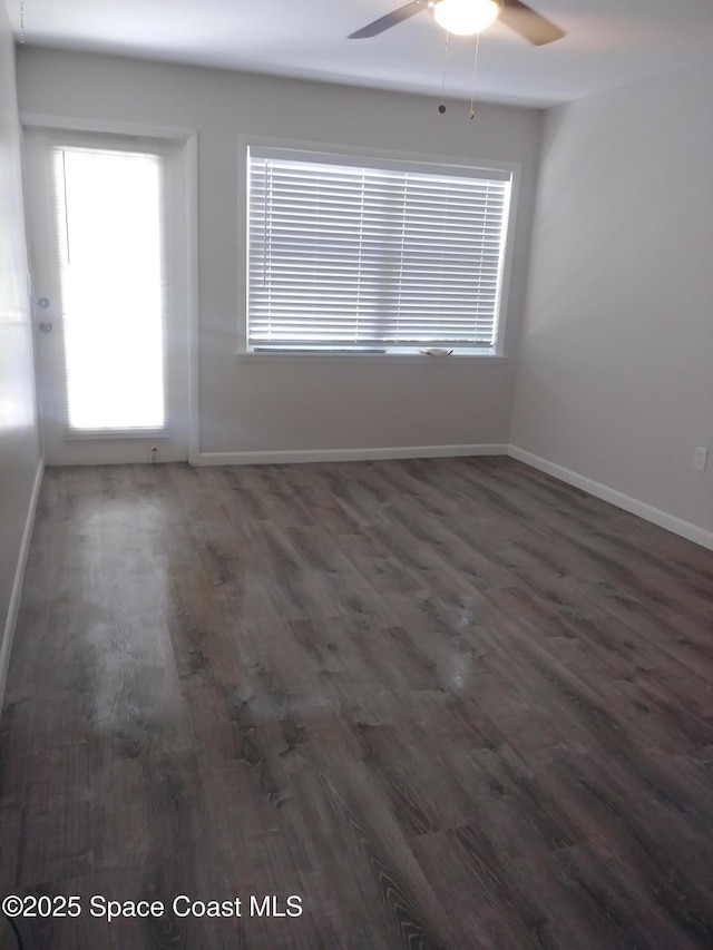 unfurnished room featuring baseboards, a ceiling fan, and dark wood-style floors