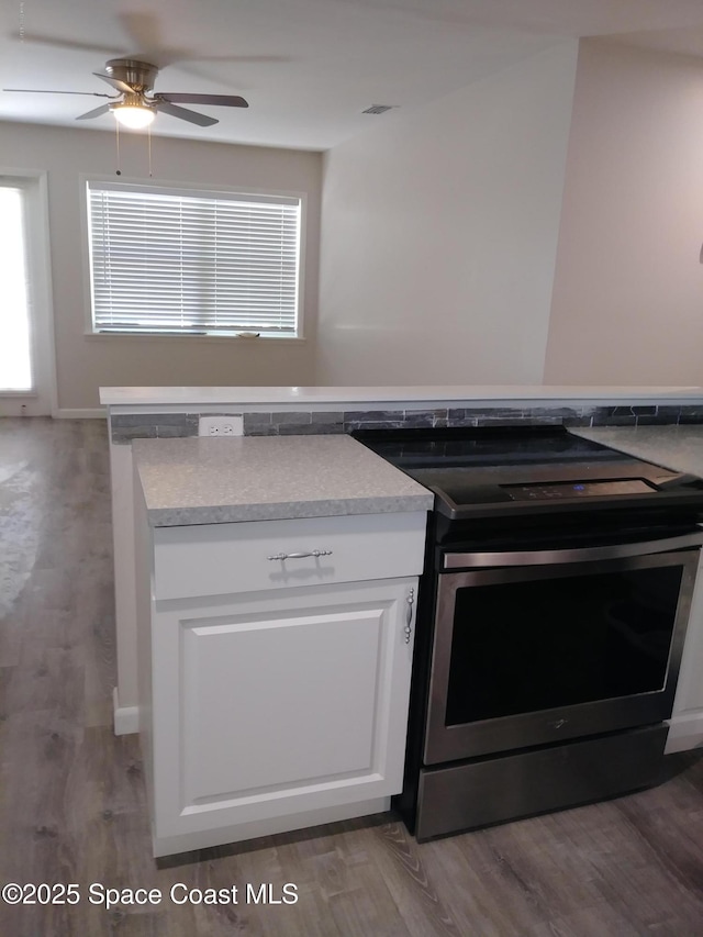 kitchen with white cabinets, a ceiling fan, stainless steel electric stove, and wood finished floors
