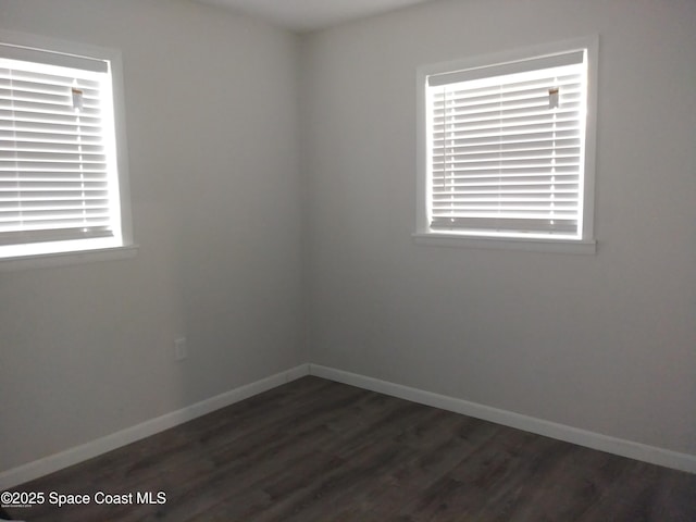 spare room featuring dark wood-style flooring and baseboards