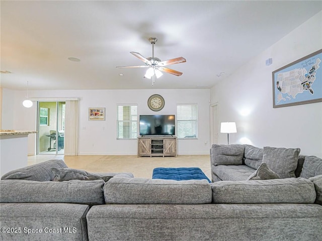 living area featuring light colored carpet, baseboards, and ceiling fan