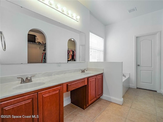 bathroom with a sink, tile patterned floors, a walk in closet, and visible vents
