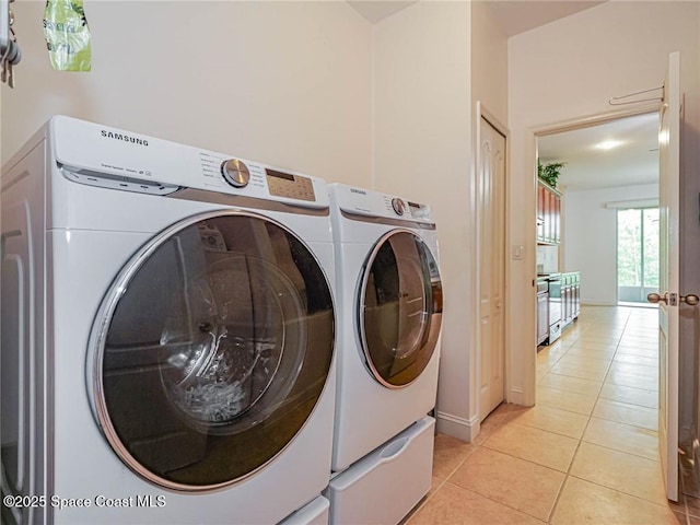 laundry room featuring baseboards, laundry area, light tile patterned flooring, and washer and dryer