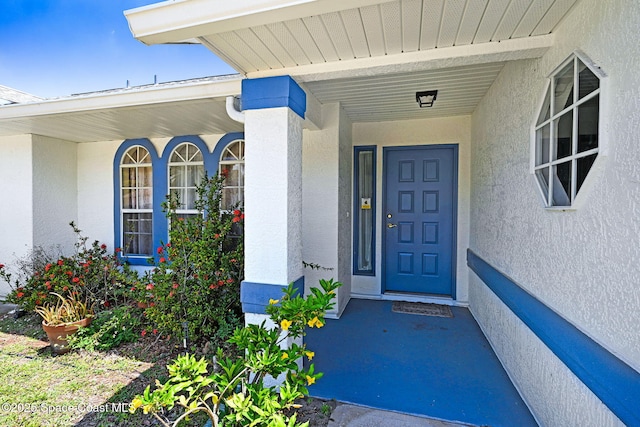 doorway to property with covered porch and stucco siding