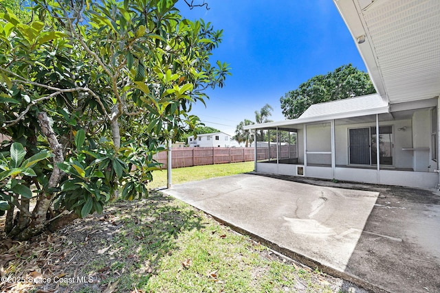 view of yard featuring fence, a patio, and a sunroom