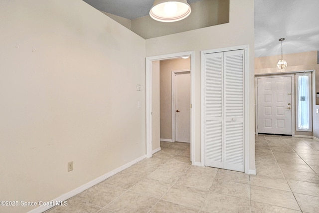 unfurnished bedroom featuring a closet, baseboards, and light tile patterned floors