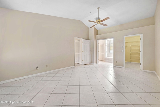 unfurnished bedroom with a ceiling fan, light tile patterned floors, baseboards, high vaulted ceiling, and ensuite bath