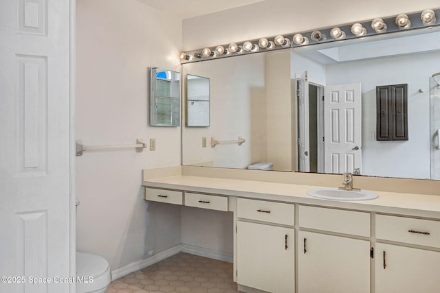 bathroom featuring vanity, tile patterned floors, baseboards, and toilet