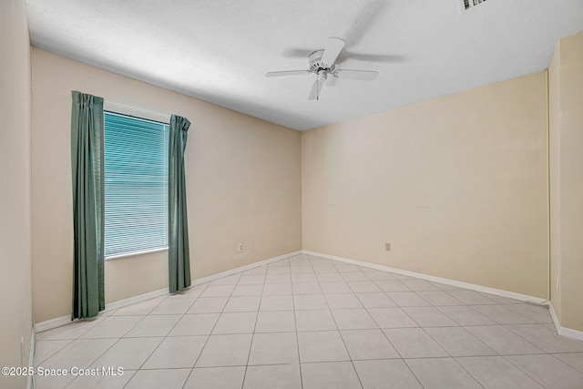 empty room featuring baseboards, a ceiling fan, a textured ceiling, and light tile patterned floors