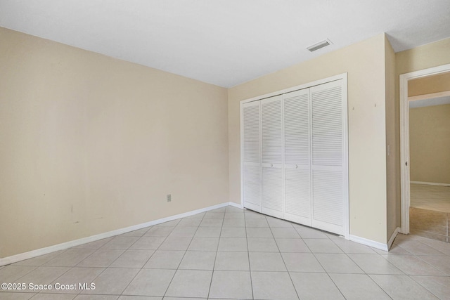 unfurnished bedroom with baseboards, visible vents, light tile patterned floors, and a closet