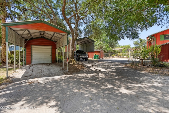 view of parking / parking lot featuring fence, driveway, and a storage shed