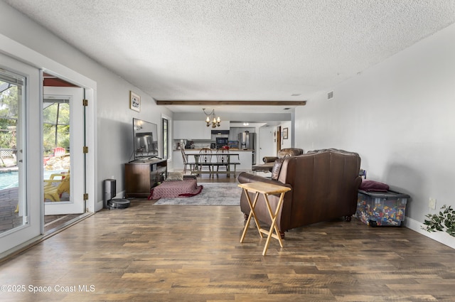 living area featuring an inviting chandelier, a textured ceiling, wood finished floors, and visible vents