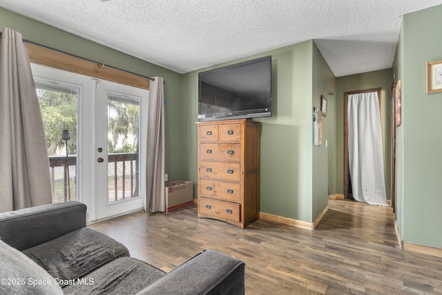 living area featuring french doors, baseboards, a textured ceiling, and wood finished floors