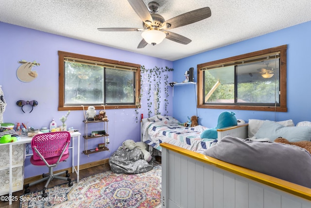 bedroom featuring a textured ceiling, wood finished floors, and multiple windows