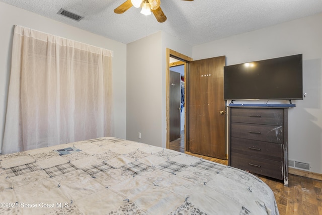 bedroom featuring ceiling fan, dark wood-style flooring, a textured ceiling, and visible vents