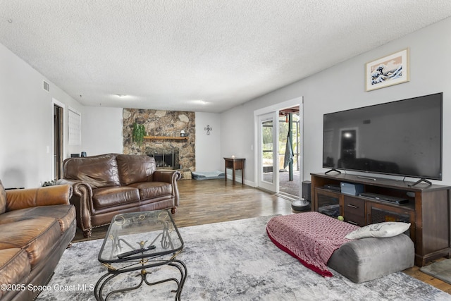 living room featuring visible vents, a textured ceiling, wood finished floors, and a fireplace