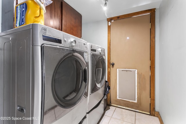 washroom featuring cabinet space, washing machine and dryer, and light tile patterned flooring