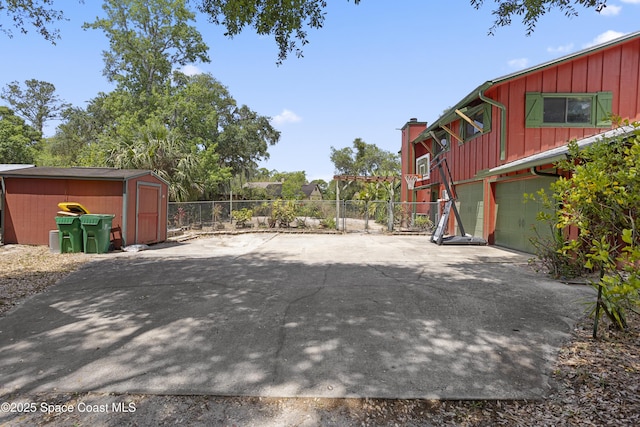 exterior space with an outbuilding, a garage, fence, a shed, and concrete driveway