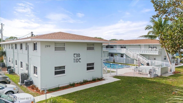 299 E Central Blvd Unit 6, Cape Canaveral, FL 32920 - rear view of property with fence, cooling unit, a community pool, stucco siding, and a lawn