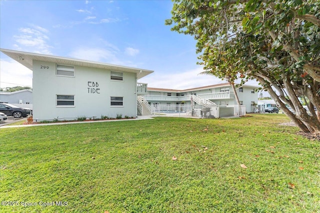 299 E Central Blvd Unit 6, Cape Canaveral, FL 32920 - back of house featuring stairway and a lawn