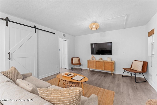 299 E Central Blvd Unit 6, Cape Canaveral, FL 32920 - living area featuring a textured ceiling, visible vents, a barn door, wood finished floors, and baseboards