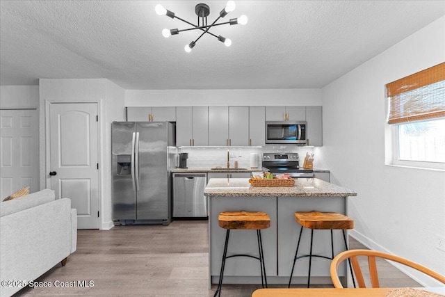 299 E Central Blvd Unit 6, Cape Canaveral, FL 32920 - kitchen with a kitchen breakfast bar, a textured ceiling, a sink, light wood-style flooring, and appliances with stainless steel finishes